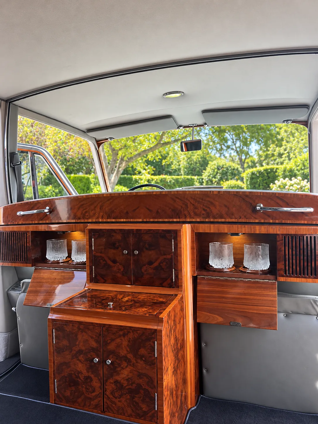 Champagne glasses and polished wood cabinetry inside a classic car