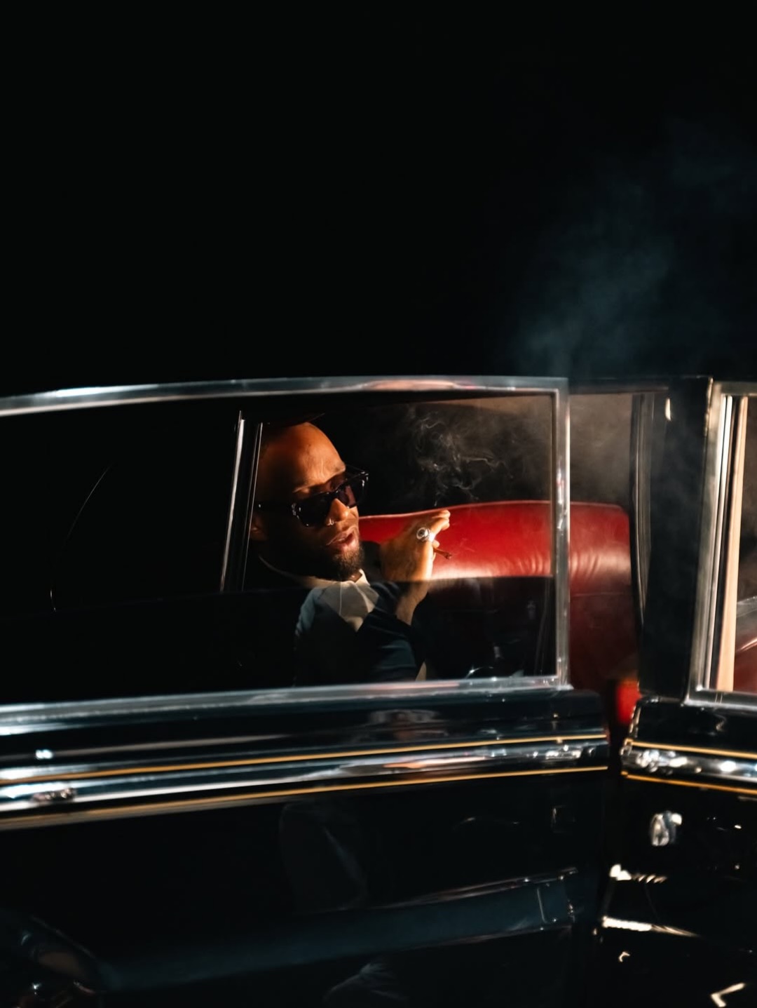 A performer seated inside a classic Rolls-Royce during a night shoot.