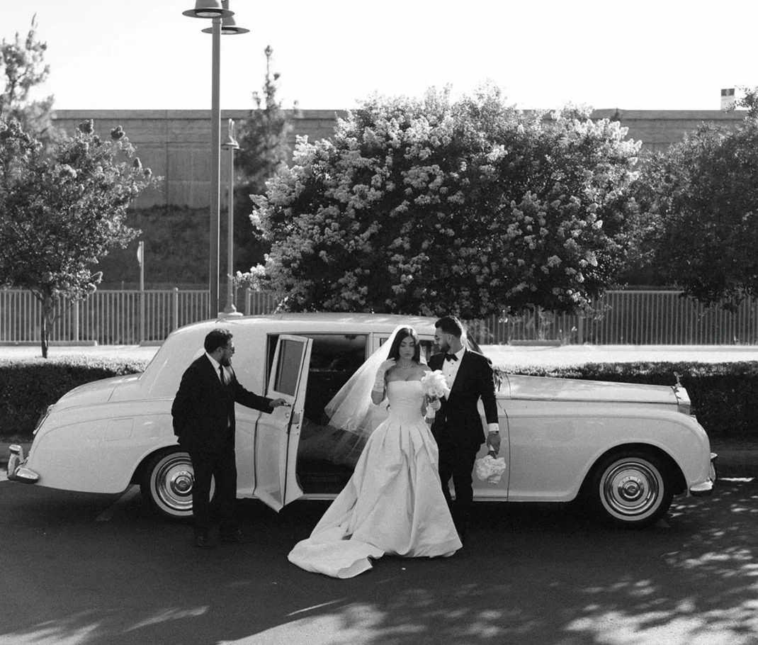 A bride and groom beside their classic white Rolls-Royce